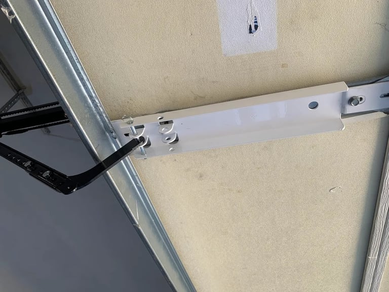 Close-up of white metal bracket mounted on beige wall with electrical outlet above